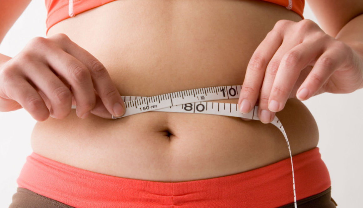 Mid adult woman measuring her waist